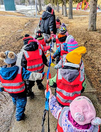 Children in safety vests on a nature walk with educators