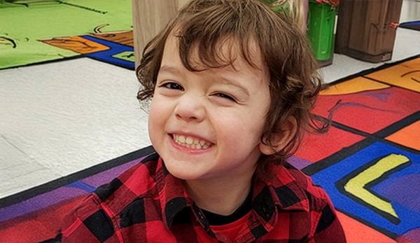 Smiling preschooler sitting on a colourful classroom rug