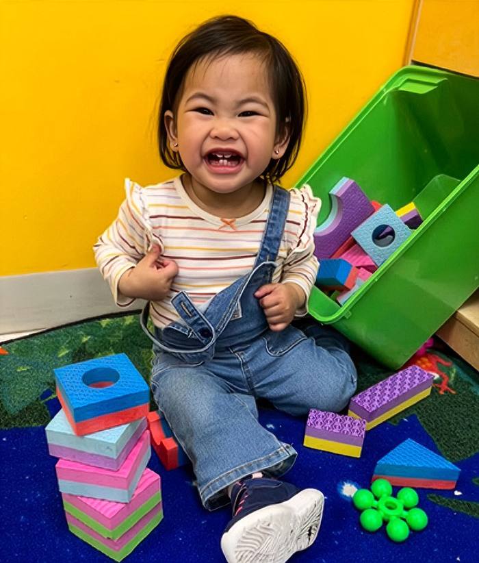 Smiling toddler playing with stacking blocks