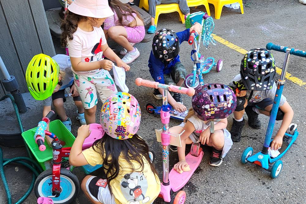 Children with scooters and helmets outdoors