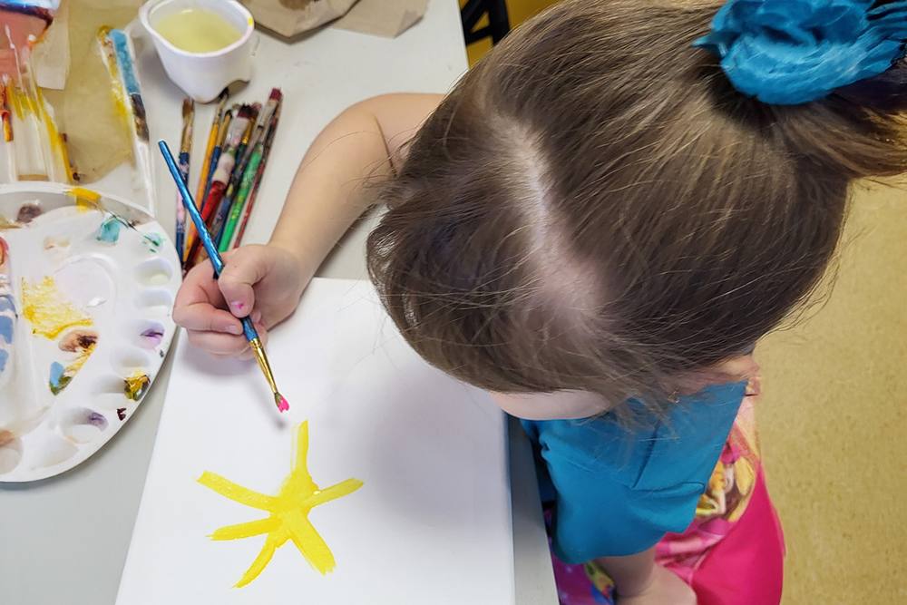 Child painting a yellow star with watercolours