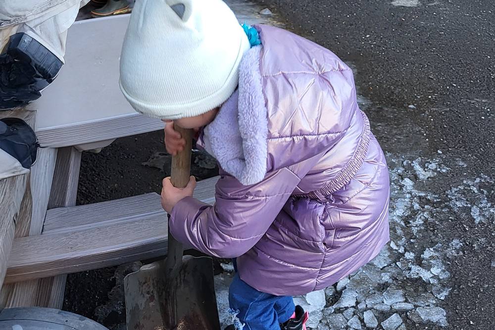 Child in winter gear digging in the snow