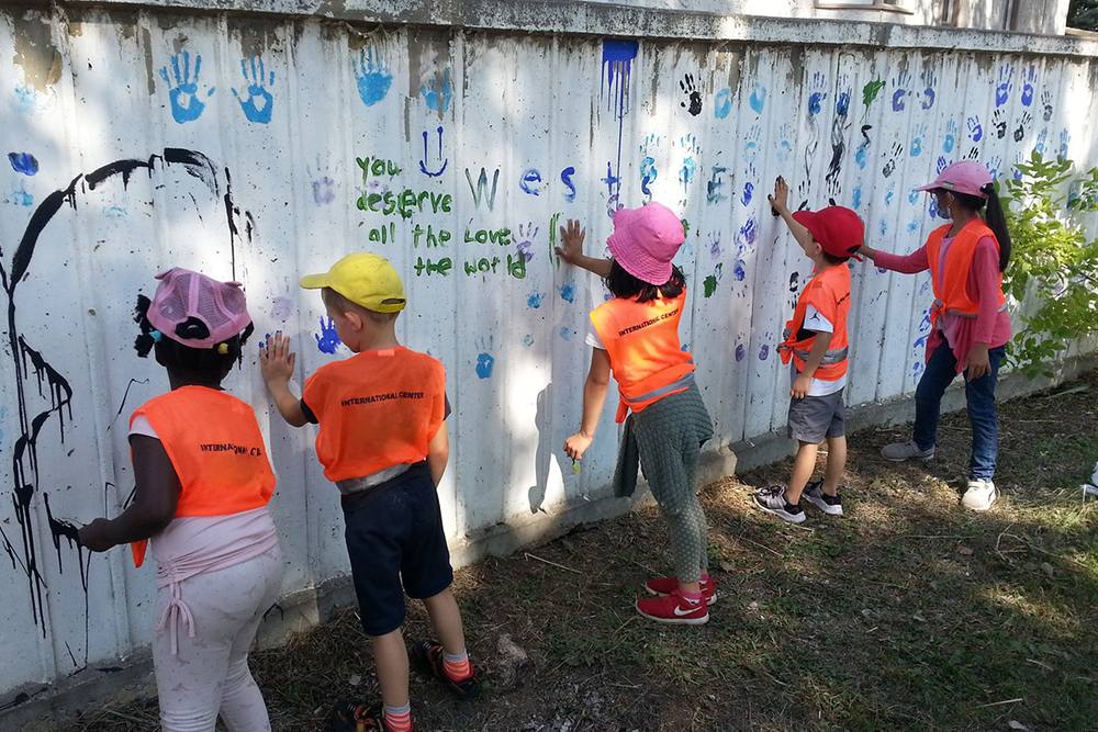 Children making handprints on an outdoor mural wall