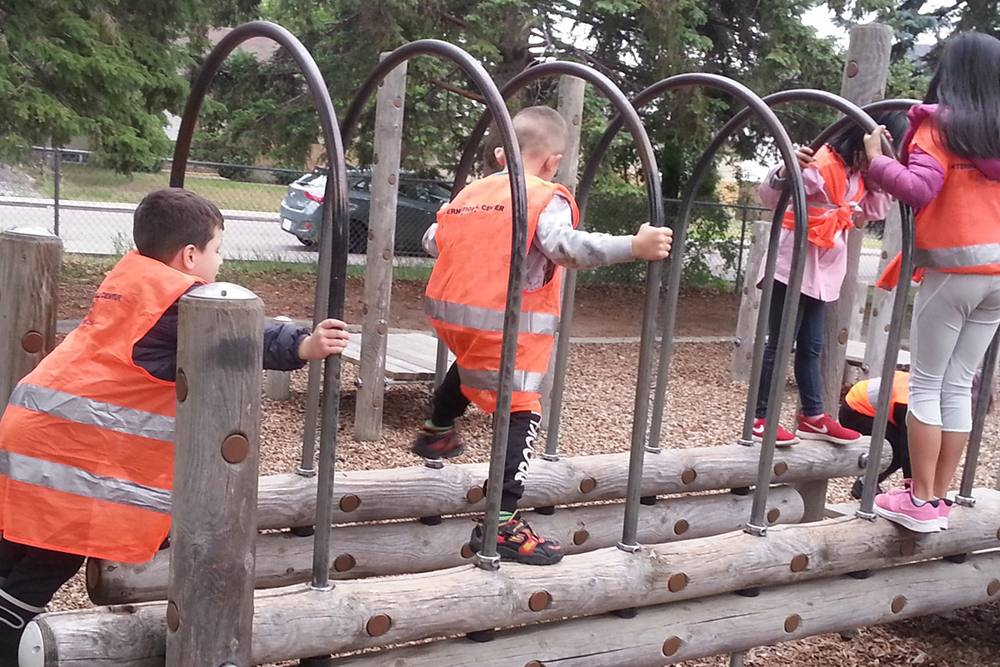 Children in safety vests climbing on a playground