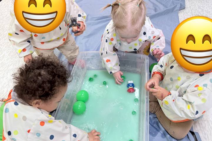 Babies exploring a water sensory bin in the baby room
