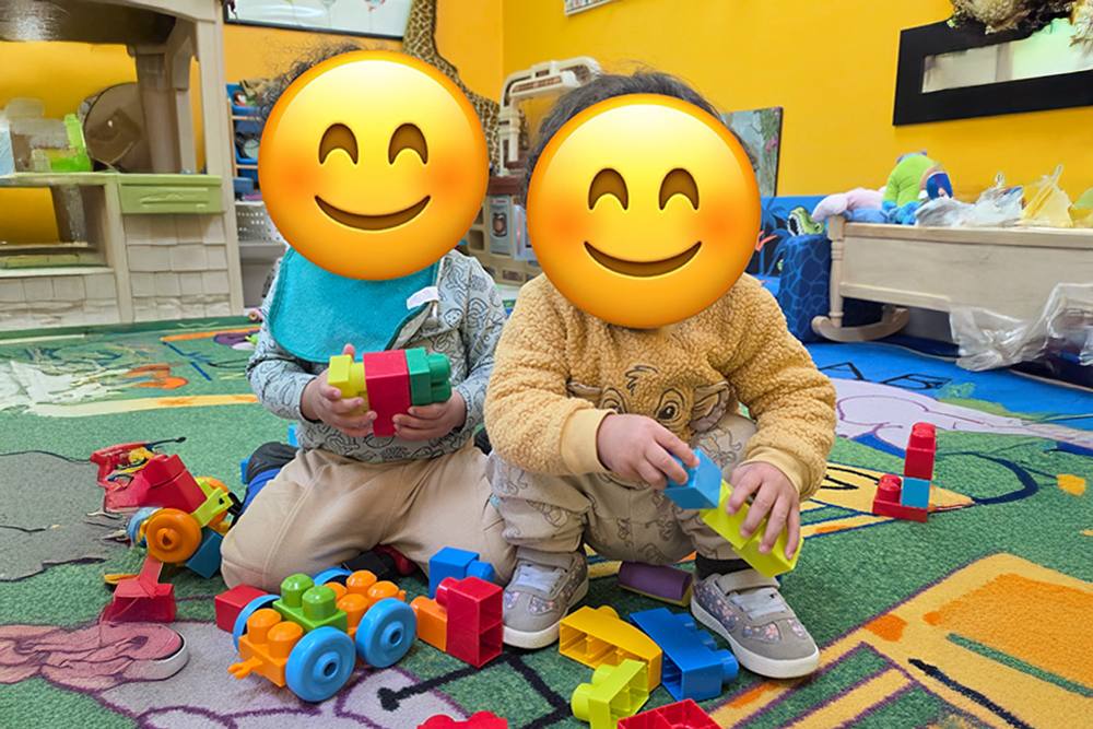 Two babies building with toy blocks on the rug