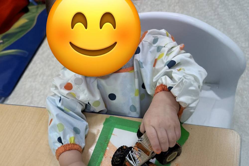 Baby rolling a toy truck across a table