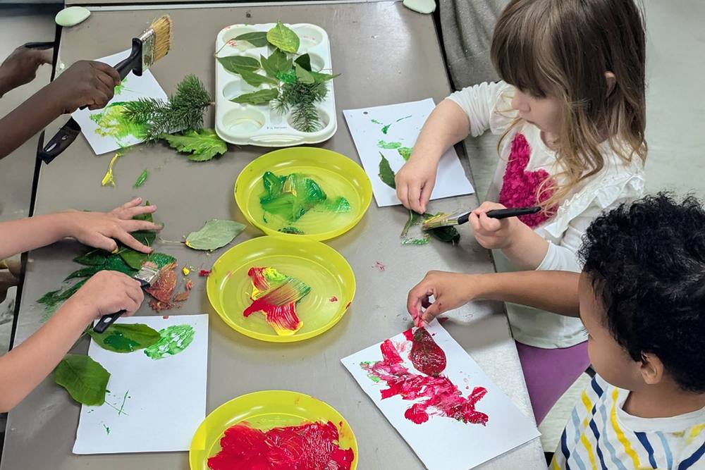 Preschoolers painting with leaves
