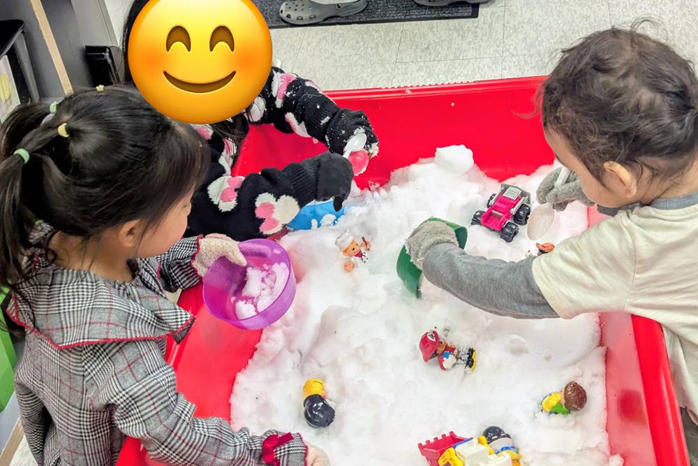 Preschoolers exploring a snow sensory bin with toys