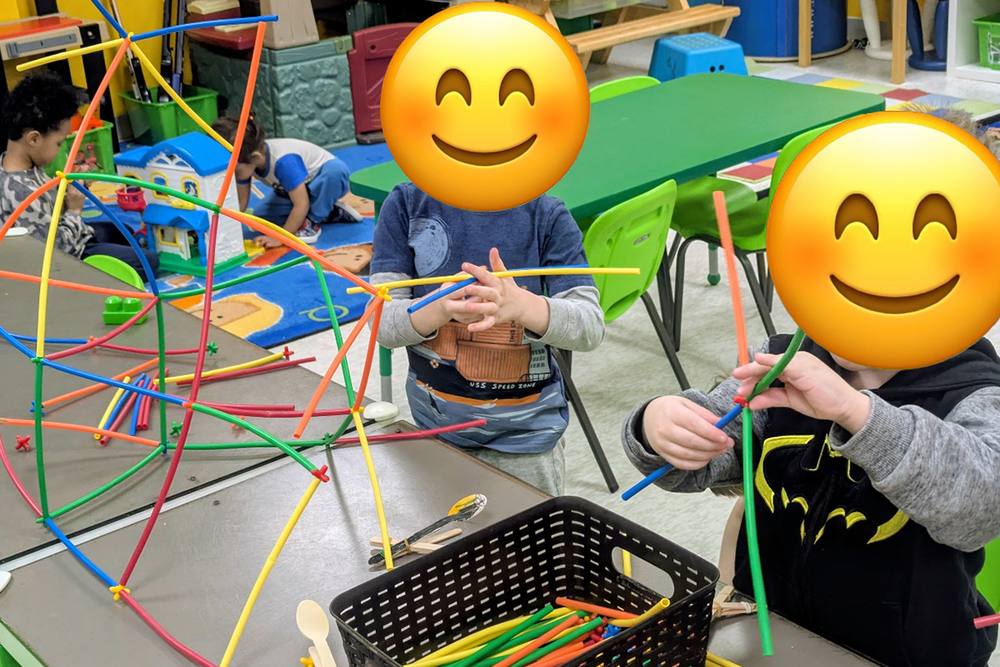 Preschoolers building with straw construction toys