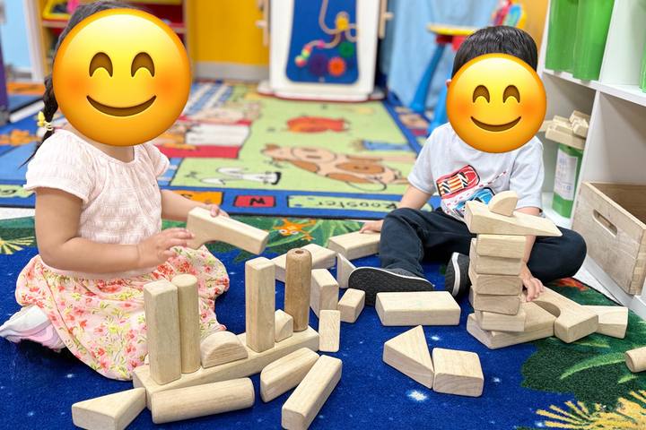 Toddlers building with wooden blocks on the classroom rug