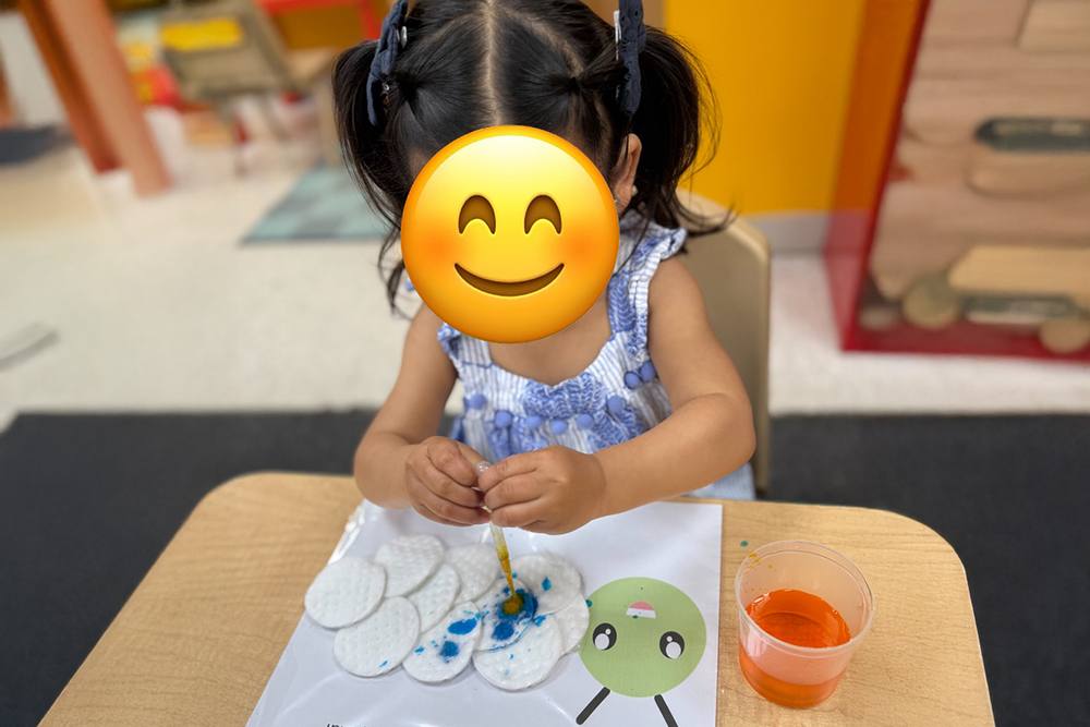 Toddler dripping coloured water onto cotton pads