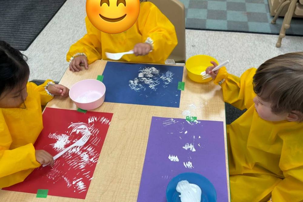 Toddlers painting on coloured paper