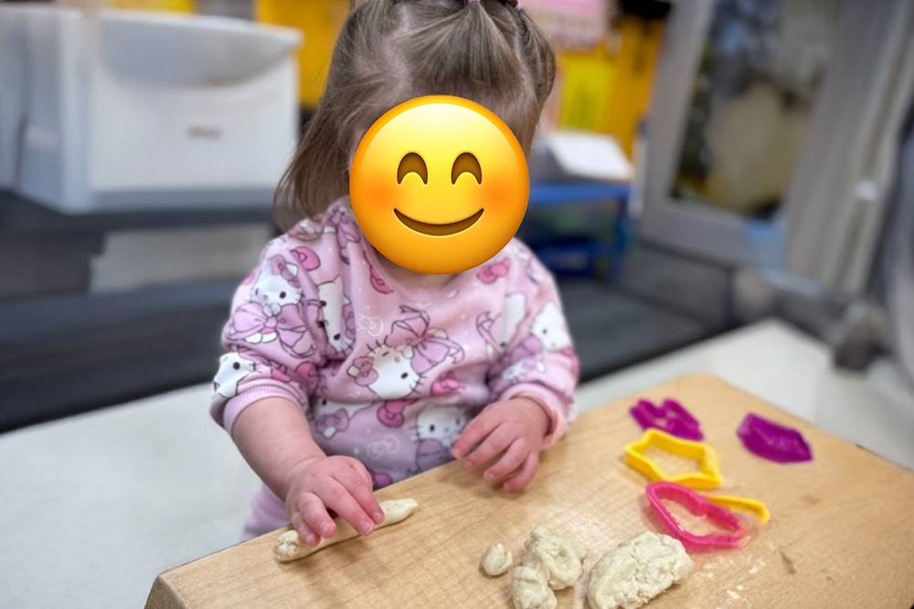 Toddler using shape cutters with play dough