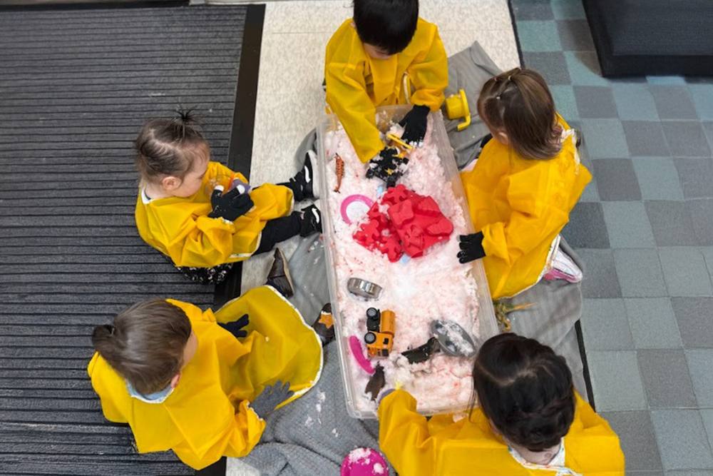 Toddlers in smocks exploring a sensory table